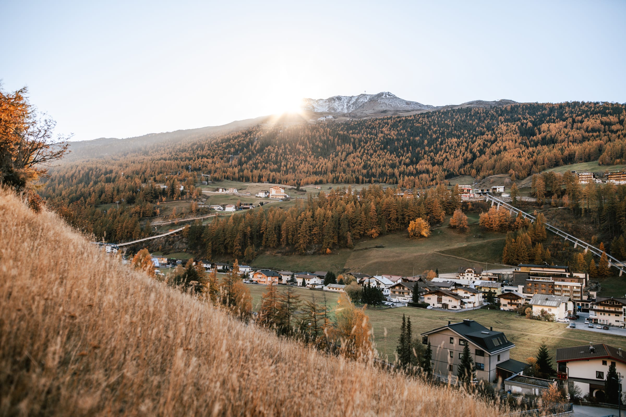 Herbstsonne über einem Ort im Ötztal mit goldenen Wäldern