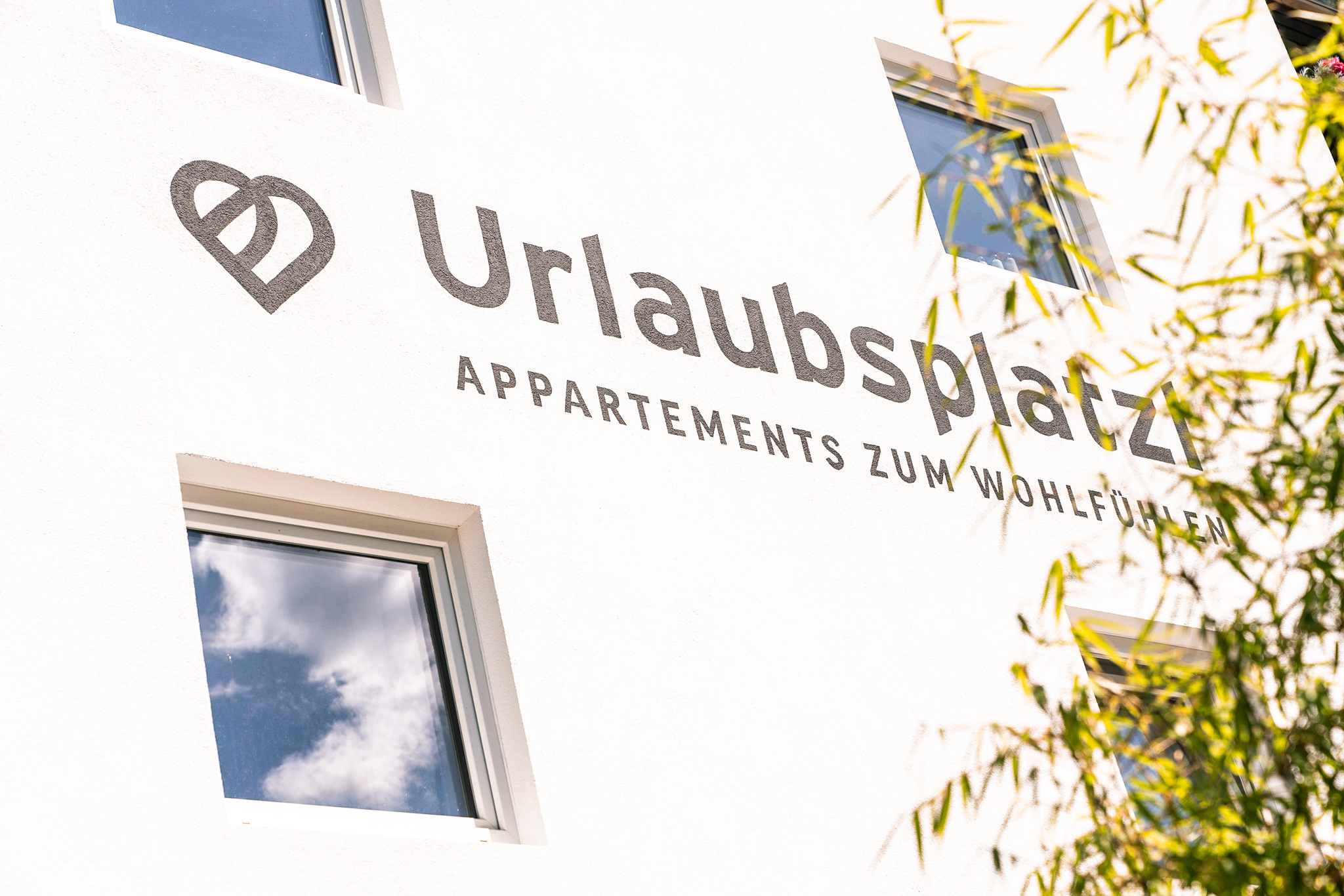 The sunny facade of Urlaubsplatzl in Oetz with its logo lettering