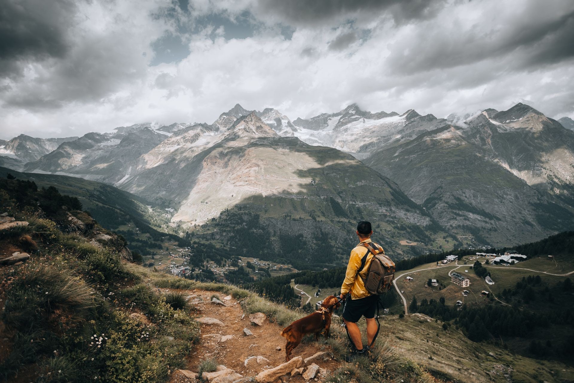 Hiker with a dog on a leash overlooking a mountain valley
